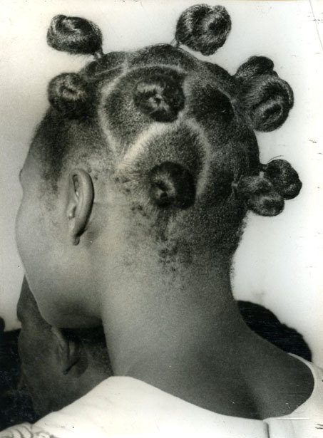 .The back view of a black girl's head, with small buns, a protective hairstyle